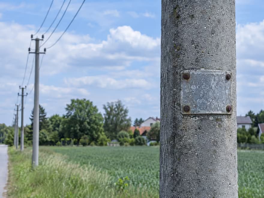 Tabliczka znamionowa przykręcona do betonowego słupa energetycznego