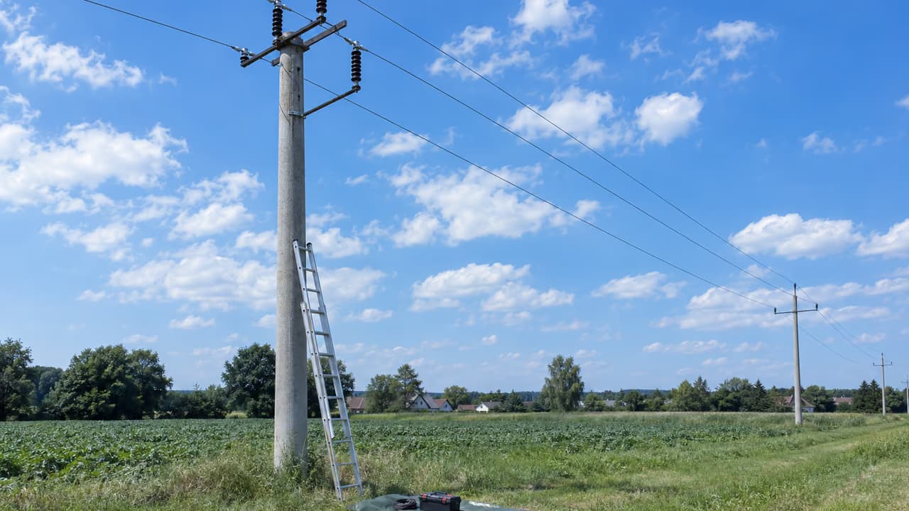 Drabina i narzędzia przy podstawie słupa energetycznego w polu